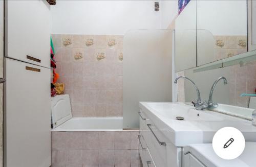 La salle de bains est pourvue d'un lavabo blanc et d'une douche. dans l'établissement Nid douillet et chaleureux pour se détendre, à Paris