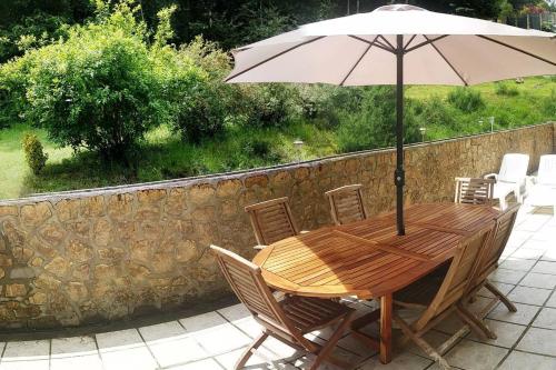 een houten tafel met een parasol op een patio bij Chambre privée dans maison au pied de la montagne noire, 5km de Mazamet in Saint-Amans-Valtoret