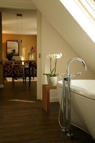 a bathroom with a bath tub and a living room at Strand-Hotel Seenelke in Wilhelmshaven