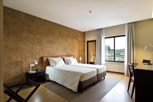 um quarto de hotel com uma cama grande e uma janela em Tulip Inn Estarreja Hotel & Spa em Estarreja
