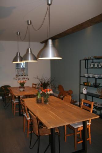 una sala da pranzo con tavoli e sedie in legno e luci di B&B Agnetenhoeve a Overasselt