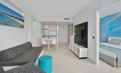 a bedroom with a couch and a bed and a tv at Aparthotel Isla de Cabrera in Colonia Sant Jordi