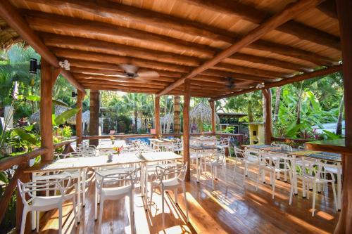 a restaurant with tables and white chairs on a wooden deck at Fuego Lodge in Santa Teresa Beach