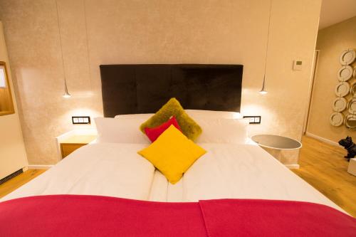 a white bed with yellow and red pillows on it at Top Hotel Hammer - Mainz Hauptbahnhof in Mainz
