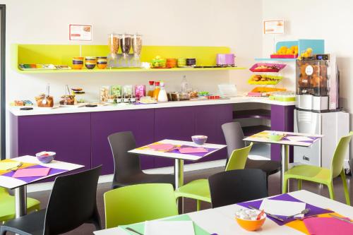 a restaurant with tables and chairs and a kitchen at ibis Styles Montbéliard in Montbéliard