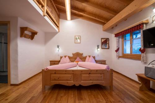 a bedroom with a large bed with pink pillows at Crusch Alba Studio auf der Strassenseite Sta Maria in Sta Maria Val Müstair