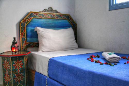 a bed with a blue headboard and a white pillow at Hotel Ouarzazate in Chefchaouene