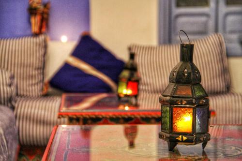 a table with a lamp on top of a table with chairs at Hotel Ouarzazate in Chefchaouene
