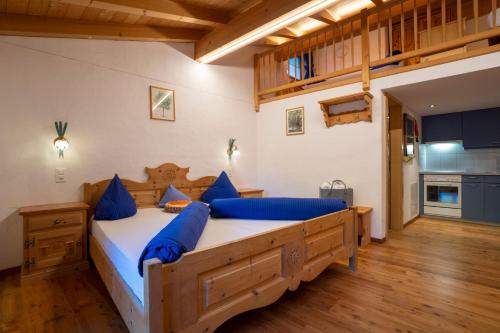 a bedroom with a large wooden bed with blue pillows at Crusch Alba Studio auf der Strassenseite Sta Maria in Sta Maria Val Müstair