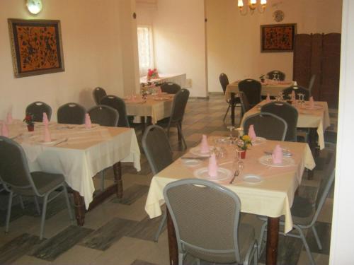 Hotel Le Fibi في ياوندي: غرفة طعام مع طاولات وكراسي بعرصي وردي