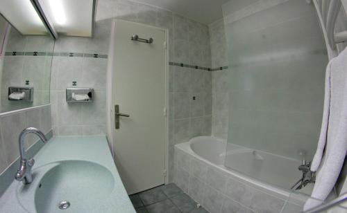 een badkamer met een bad, een wastafel en een bad bij Hotel Le Val Chavière in Val Thorens
