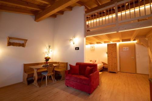 a living room with a red chair and a table at Crusch Alba Studio auf der Strassenseite Sta Maria in Sta Maria Val Müstair