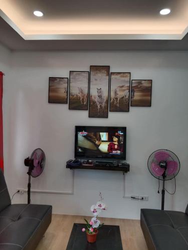 a living room with a tv on a wall with pictures at 2BR townhouses good for 12pax each & NETFLIX & 100Mbps WIFI & pool resort 2min walk & 3km outside Pico de Loro Cove & Calayo Cove - with Endorsement for Pico de Loro Cove good for 7 days & Boat-Tour & Island Hopping assistance in Nasugbu