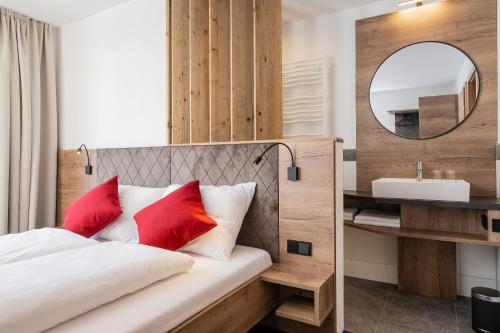 a bedroom with a bed with red pillows and a mirror at Bergappartements Pröll in Kleinarl