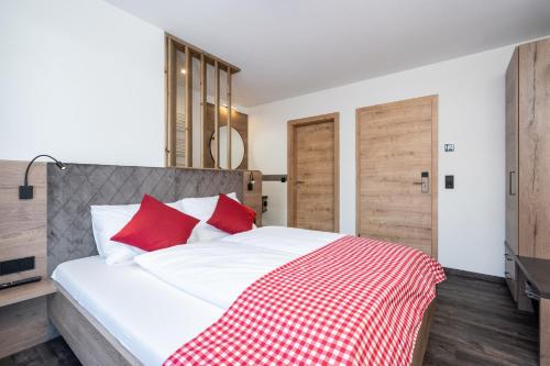 a bedroom with a white bed with red pillows at Bergappartements Pröll in Kleinarl