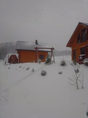 a house with snow on the ground in front of it at Domki pod Bukowym lasem in Wańkowa