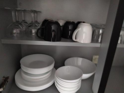 a shelf with plates and cups and dishes in a kitchen at Bel appartement en plein coeur de ville in Le Creusot
