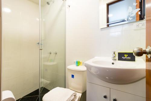 La salle de bains blanche est pourvue d'un lavabo et d'une douche. dans l'établissement Ayenda 1069 Alfay, à Bogotá