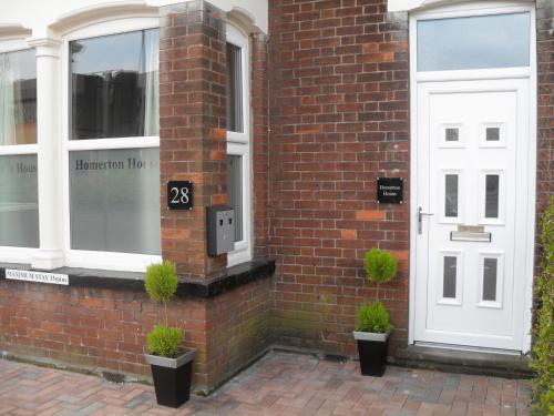 a brick building with a white door and two potted plants at Homerton House Apartments in Cambridge