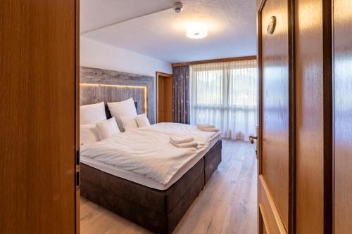 a bedroom with a large bed with white sheets at Hotel ZUM STERNENHOF in Kössen