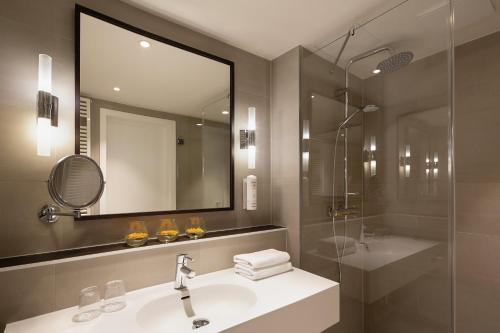 bagno con lavandino, doccia e specchio di Holiday Inn Berlin City Center East Prenzlauer Berg, an IHG Hotel a Berlino