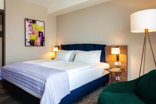 a bedroom with a large bed and a green chair at Holiday Inn Berlin City Center East Prenzlauer Berg by IHG in Berlin