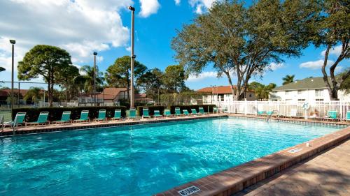 a large swimming pool with chairs and trees at Shorewalk Vacation Villa in Bradenton