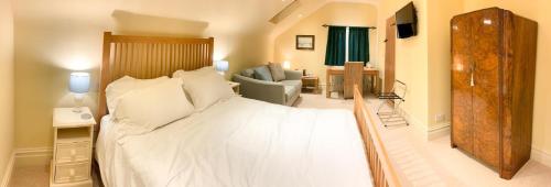 a bedroom with a white bed and a living room at Hollies Farm B&B in Wrexham