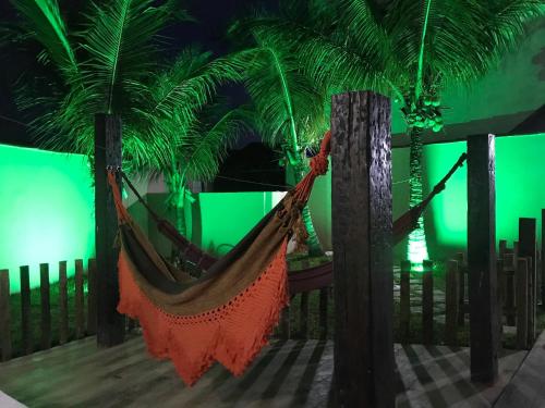a hammock hanging from two palm trees with a green screen at Pousada Bonanza in Arraial do Cabo