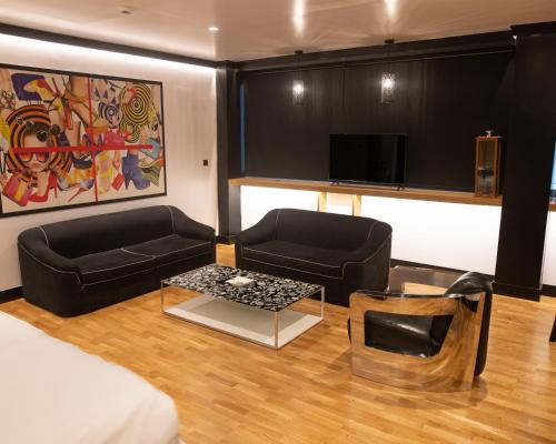 sala de estar con 2 sofás negros y TV en Andromeda Downtown Residence, en Atenas