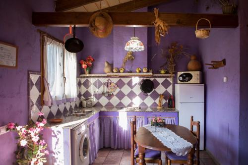 a kitchen with purple walls and a table and chairs at Lo Racó de Peret in Camarles