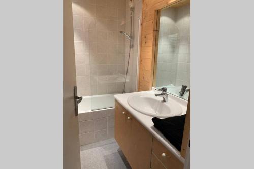 a bathroom with a sink and a mirror and a tub at Alpe d'Huez centre de la station résidence Athos in L'Alpe-d'Huez