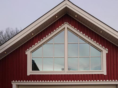 a large window on a red barn at Myntloftet Borlänge med inglasad bubbelbad in Borlänge