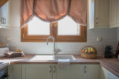 a kitchen with a sink and a window and a basket of fruit at ONOMY Country House Vathypetro in Archanes