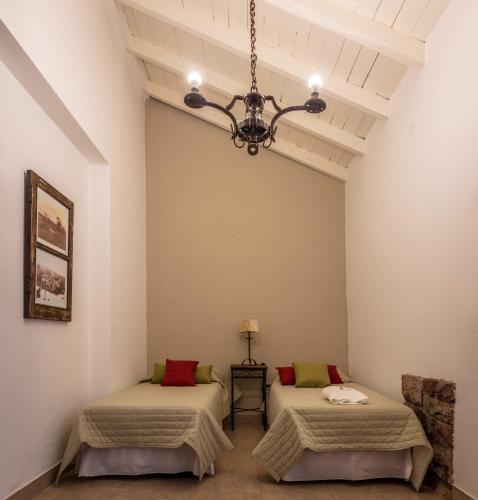 a room with two beds and a chandelier at Hotel del Ingenio in Libertador General San Martín