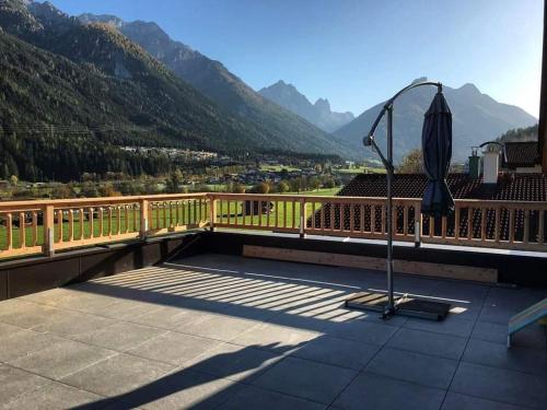 an umbrella on a balcony with mountains in the background at Ferienlandhaus Höfer in Fulpmes
