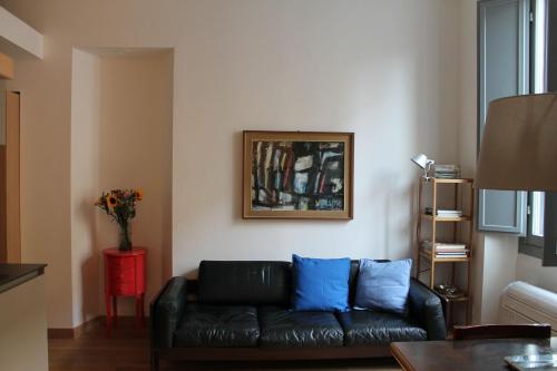 salon z czarną skórzaną kanapą i niebieskimi poduszkami w obiekcie Goldoni77 w Mediolanie