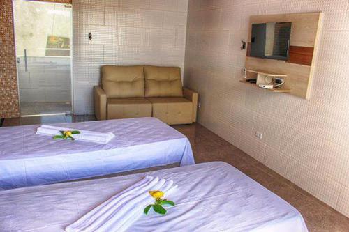a hotel room with two beds and a couch at FLAT RIOMAR in Coruripe