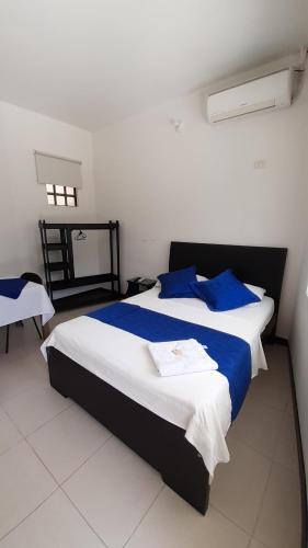 a bedroom with a large bed with blue pillows at Hotel Zenit de Colombia in Puerto López