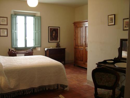 a bedroom with a bed and a desk and a window at Agriturismo La Capitata in Pian di Scò