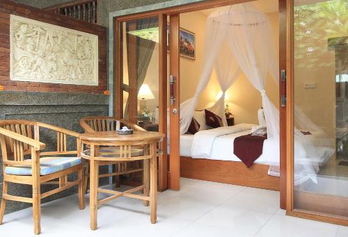 a bedroom with a bed and a table and a chair at Jerogadung House in Ubud