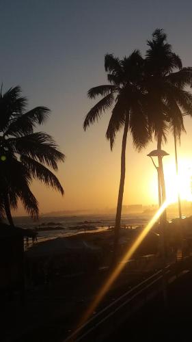 a sunset on the beach with palm trees at CASACOMPART itapuã in Salvador
