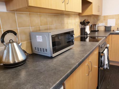 a kitchen counter with a microwave and a tea kettle at Inverness City Centre Apartment with Elevator and Google Chromecast in Inverness