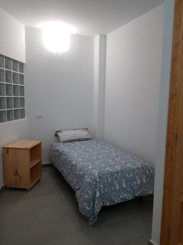 ein kleines Schlafzimmer mit einem Bett und einem Holzschrank in der Unterkunft Apartamento privado en una zona tranquila y próxima al aeropuerto TF norte y a la ciudad de San Cristóbal de la Laguna . in La Laguna