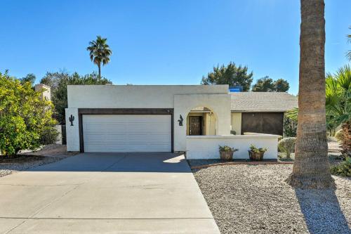 a white house with a garage and a palm tree at 7 Mi to Riparian Preserve Family Home with Yard! in Mesa