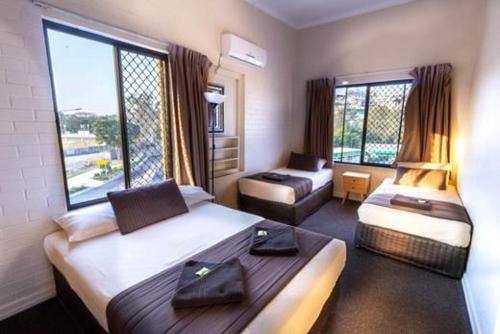 a hotel room with two beds and a couch at Kingsford Riverside Inn in Brisbane