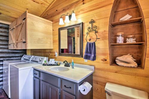 a bathroom with a sink and a washer and dryer at Arkansas Log Cabin Rental Near Lake Greeson! in Mount Moriah