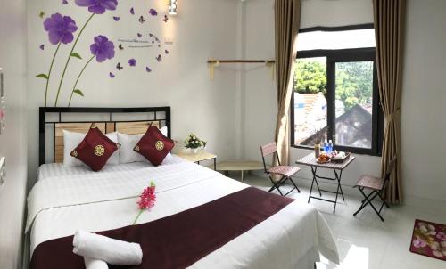 une chambre avec un grand lit blanc avec des fleurs violettes sur le mur dans l'établissement Thăng Loan Tam Cốc Hostel, à Ninh Binh