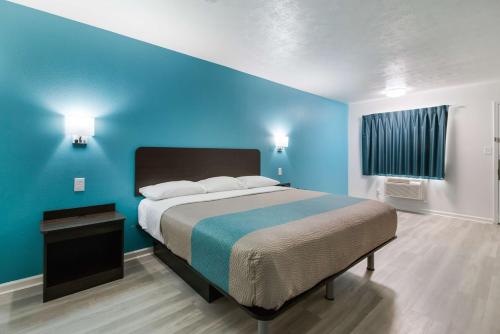 a bedroom with a bed with a blue wall at Motel 6-Metropolis, IL in Metropolis