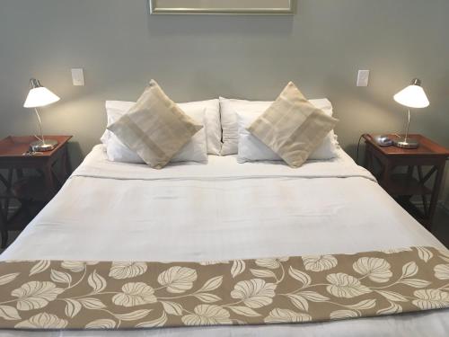 a bed with a white comforter and pillows on it at Shangri-La Gardens in Brisbane